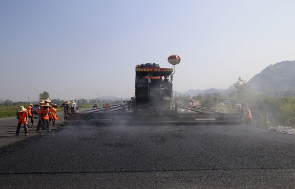 2019年8月，宜春經(jīng)開區(qū)S311路面攤鋪現(xiàn)場，工友們輔助路面兩側(cè)的分料、補窩等作業(yè)